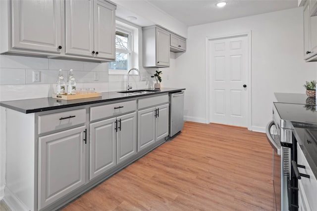 kitchen with gray cabinets, tasteful backsplash, dishwasher, sink, and light wood-type flooring