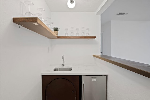 bar with sink and stainless steel fridge