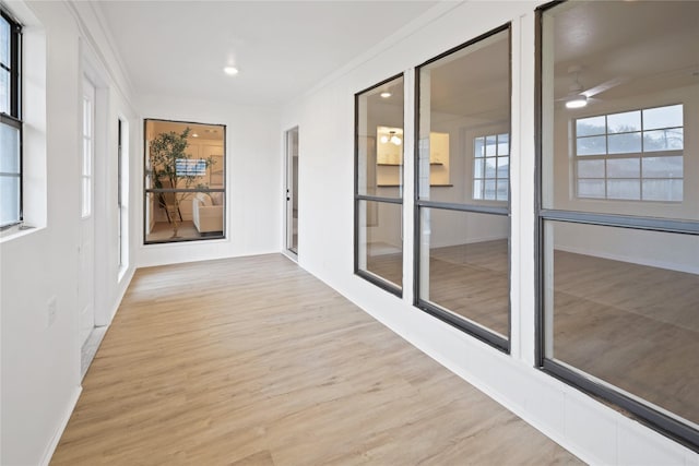 hallway with crown molding and light hardwood / wood-style flooring