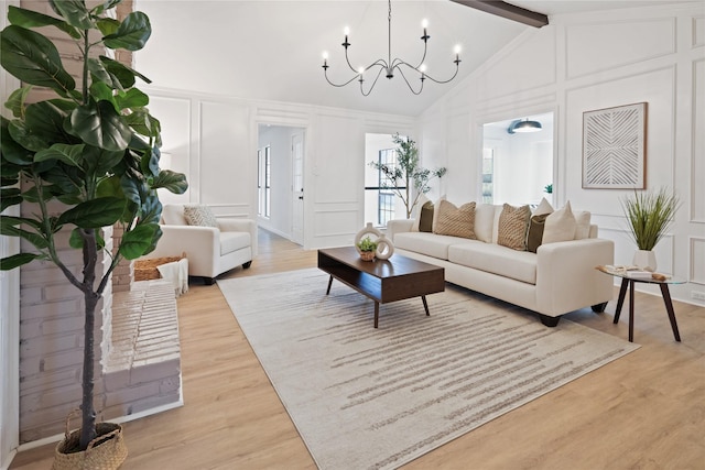 living room with a notable chandelier, lofted ceiling with beams, and light wood-type flooring