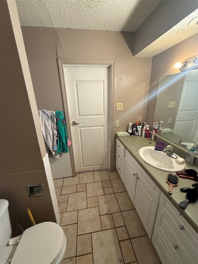 bathroom featuring tile patterned floors, a textured ceiling, vanity, and toilet