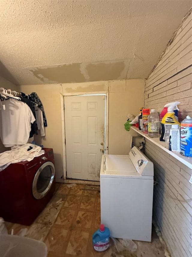 washroom featuring brick wall, washer / clothes dryer, and a textured ceiling