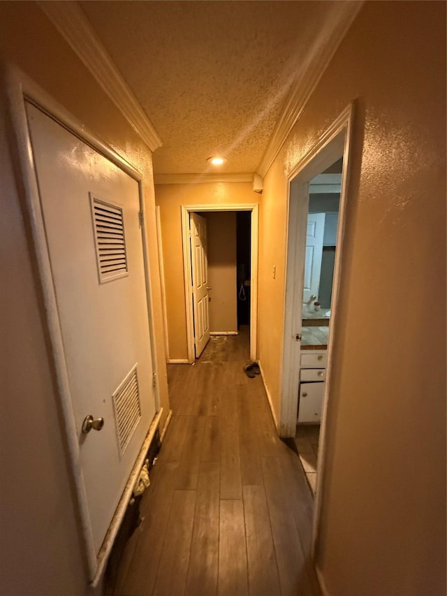 corridor featuring ornamental molding, dark wood-type flooring, and a textured ceiling