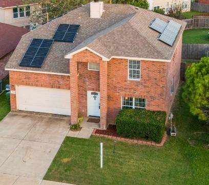 view of front of house featuring a garage, a front yard, and solar panels