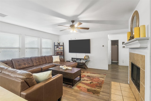 living room with a fireplace, ceiling fan, and light wood-type flooring