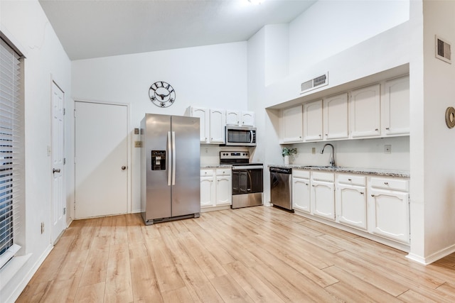 kitchen featuring sink, appliances with stainless steel finishes, white cabinetry, high vaulted ceiling, and light hardwood / wood-style floors