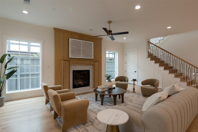 living room featuring ornamental molding, a wealth of natural light, ceiling fan, and light wood-type flooring