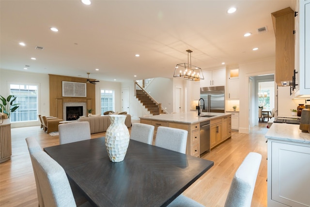 dining space with crown molding, a large fireplace, a wealth of natural light, and light hardwood / wood-style floors