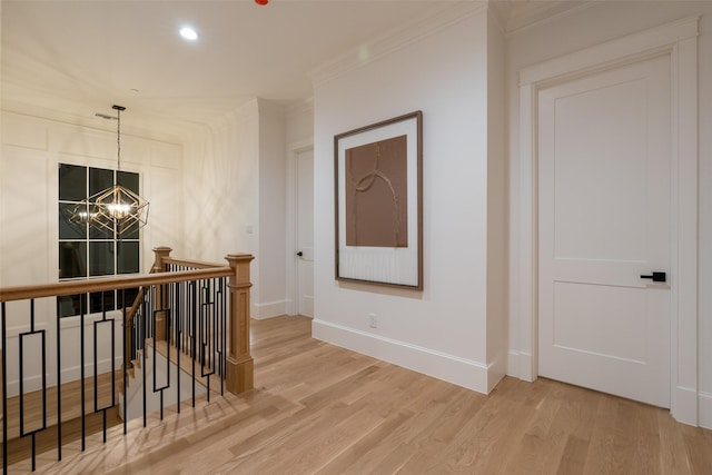 hall with an inviting chandelier, crown molding, and wood-type flooring