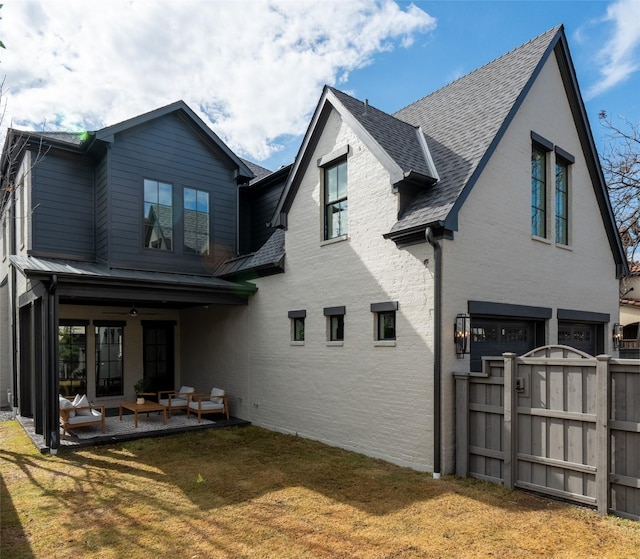 rear view of house with a garage, a yard, and a patio area