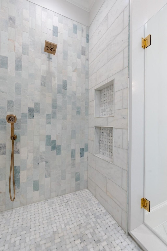 bathroom with crown molding and a tile shower