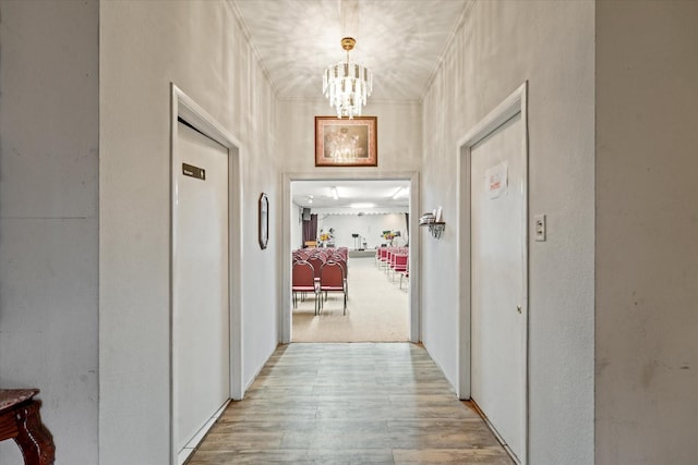 hallway featuring a notable chandelier and light hardwood / wood-style floors