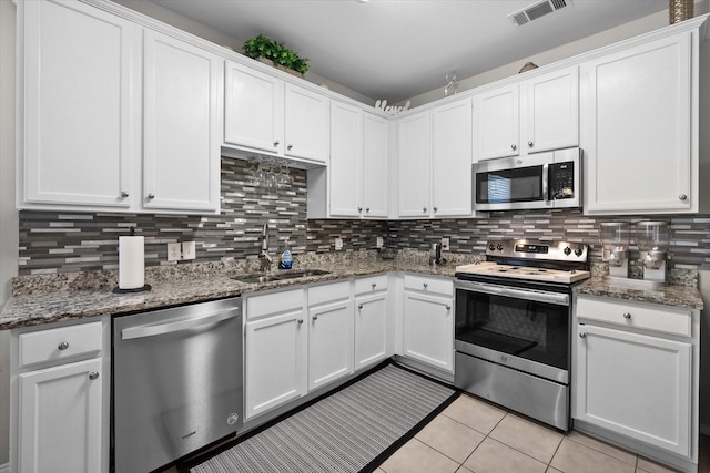 kitchen featuring sink, white cabinetry, tasteful backsplash, dark stone countertops, and stainless steel appliances