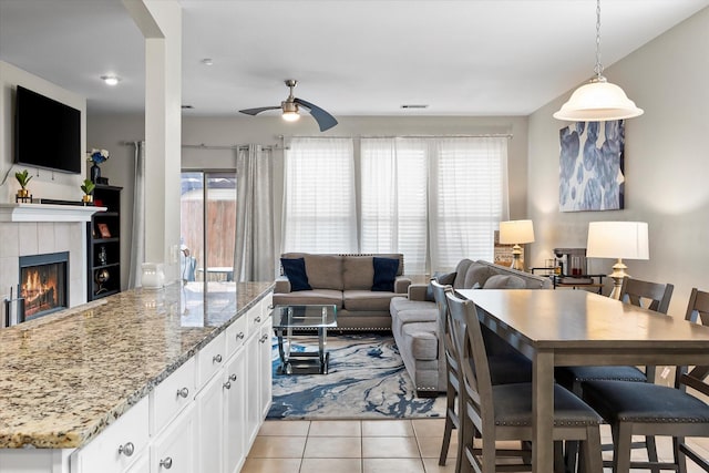 kitchen with pendant lighting, a wealth of natural light, white cabinetry, light tile patterned floors, and light stone countertops