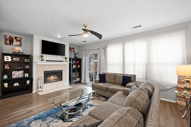 living room featuring hardwood / wood-style flooring, ceiling fan, and a tile fireplace