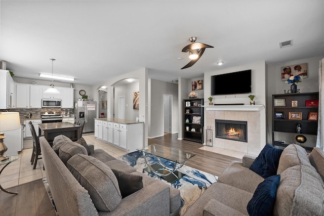 living room with a tiled fireplace and light hardwood / wood-style flooring