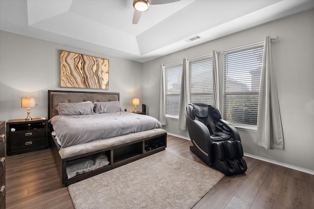 bedroom featuring dark hardwood / wood-style flooring, a raised ceiling, and ceiling fan