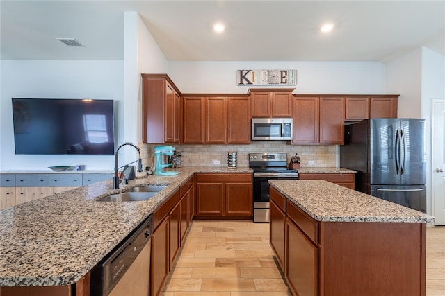 kitchen featuring sink, backsplash, kitchen peninsula, stainless steel appliances, and light stone countertops