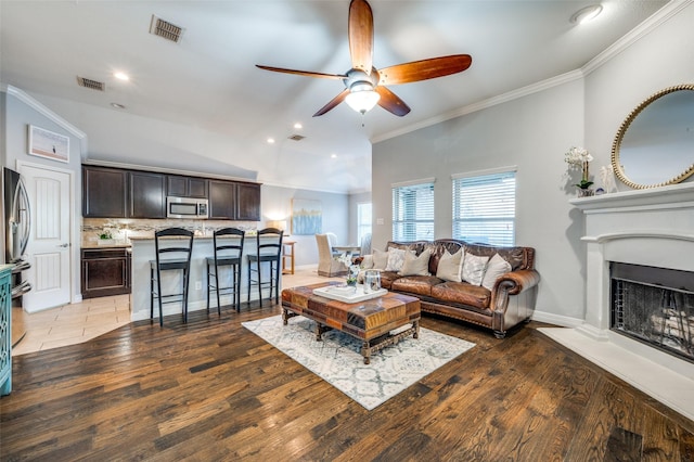 living room with crown molding, lofted ceiling, dark wood-type flooring, and ceiling fan