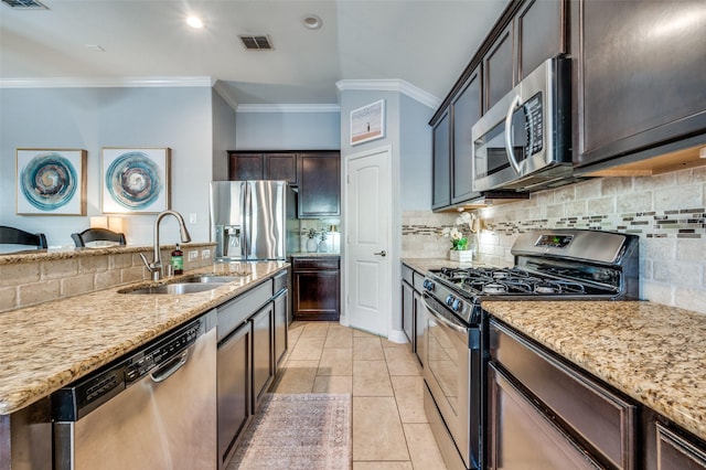 kitchen featuring tasteful backsplash, sink, light stone counters, and appliances with stainless steel finishes