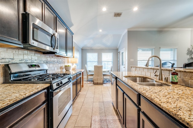 kitchen with sink, backsplash, stainless steel appliances, light stone countertops, and dark brown cabinets