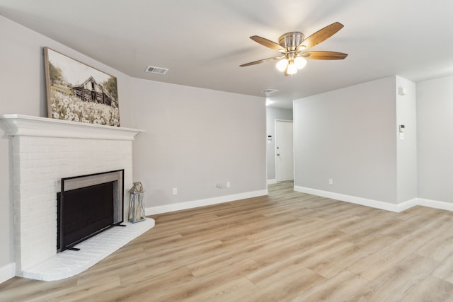 unfurnished living room featuring a brick fireplace, light hardwood / wood-style floors, and ceiling fan