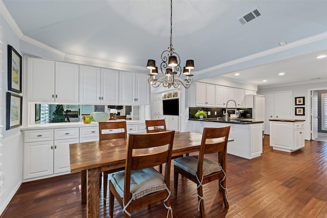 kitchen featuring dark hardwood / wood-style floors, pendant lighting, white cabinetry, ornamental molding, and a center island