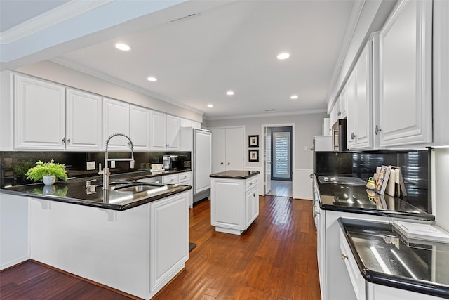 kitchen featuring white cabinetry, sink, kitchen peninsula, crown molding, and dark wood-type flooring