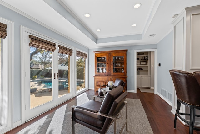 interior space with dark hardwood / wood-style floors, ornamental molding, a tray ceiling, and french doors