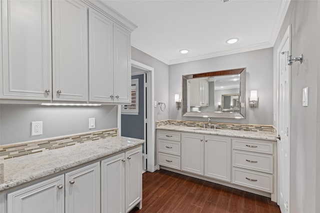 bathroom with crown molding, wood-type flooring, tasteful backsplash, and vanity