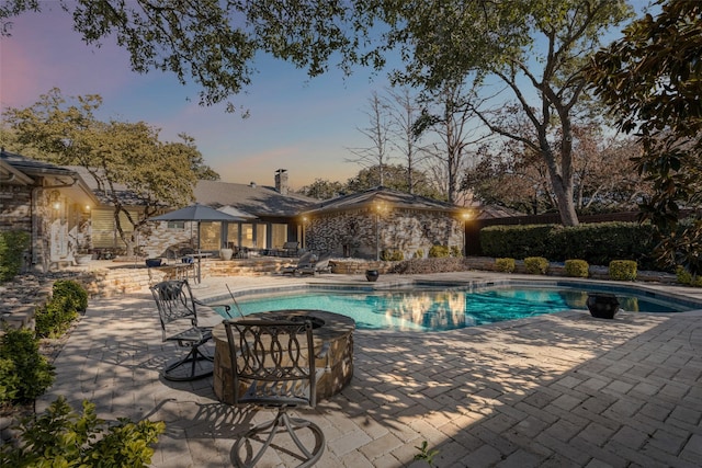 pool at dusk featuring a patio