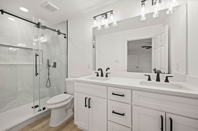 bathroom with wood-type flooring, toilet, vanity, and a shower with shower door