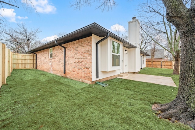 view of side of home featuring a patio and a lawn