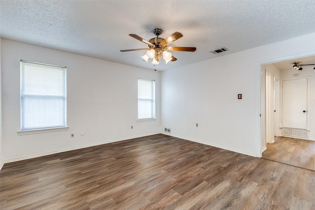 empty room featuring dark wood-type flooring, a textured ceiling, and ceiling fan