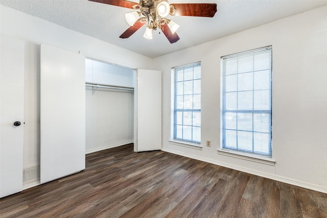 unfurnished bedroom with ceiling fan, dark hardwood / wood-style floors, a closet, and a textured ceiling