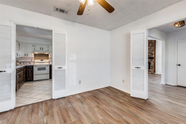 kitchen featuring ceiling fan, white range with electric cooktop, a textured ceiling, and light wood-type flooring