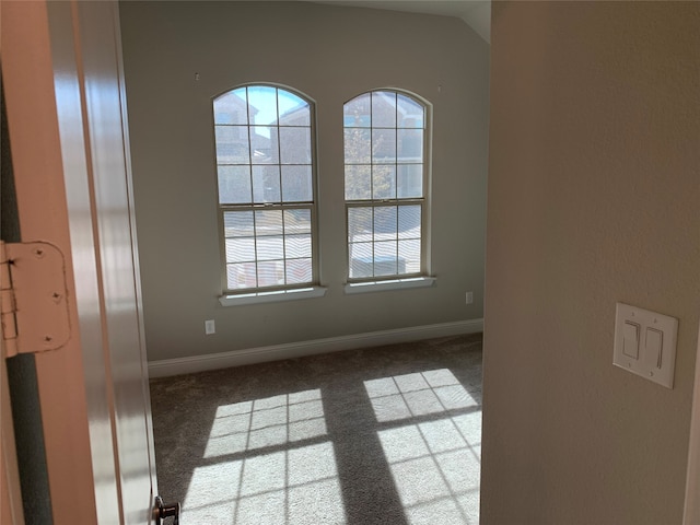 carpeted empty room with plenty of natural light and vaulted ceiling