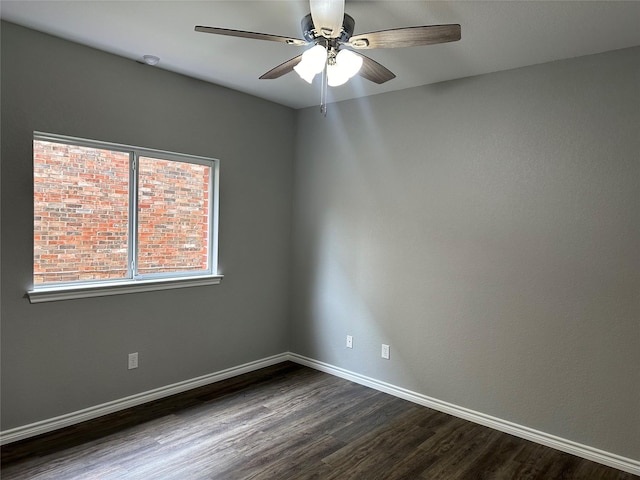 spare room with dark wood-style flooring, ceiling fan, and baseboards