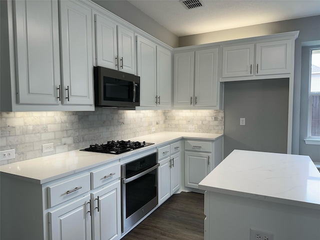 kitchen featuring visible vents, white cabinetry, black gas stovetop, and oven