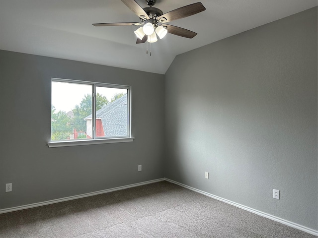 carpeted empty room with vaulted ceiling, a ceiling fan, and baseboards