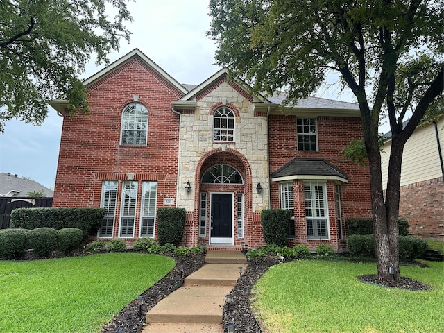 traditional-style home with a front yard, stone siding, and brick siding