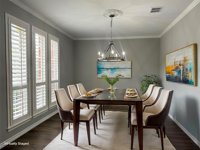 dining space featuring dark wood-style flooring, crown molding, a notable chandelier, visible vents, and baseboards