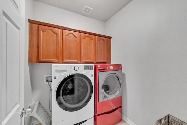 clothes washing area with washer and dryer and cabinets