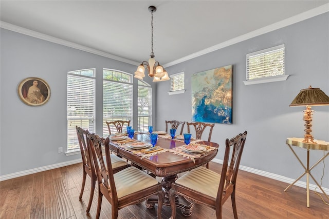 dining space with hardwood / wood-style flooring, ornamental molding, and an inviting chandelier