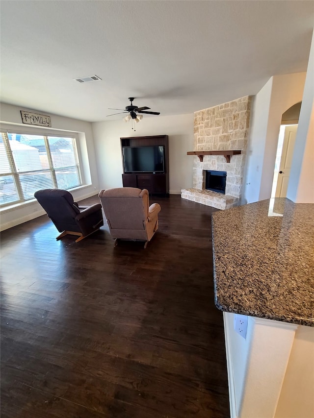 living room featuring ceiling fan, a fireplace, and dark hardwood / wood-style flooring