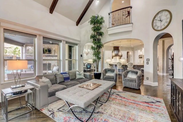 living area featuring arched walkways, dark wood-style floors, beamed ceiling, high vaulted ceiling, and a notable chandelier