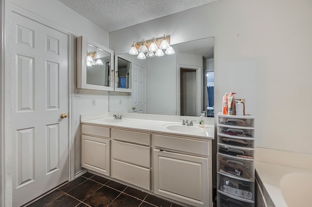 bathroom featuring tile patterned floors, a bath, a textured ceiling, and vanity