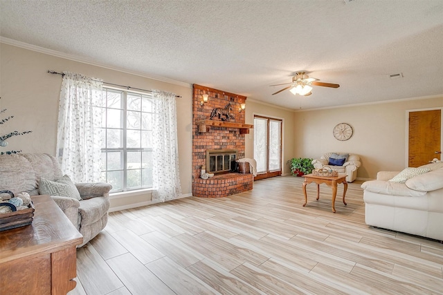 living room featuring a fireplace, ceiling fan, crown molding, a textured ceiling, and light wood-type flooring