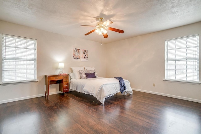 bedroom with multiple windows, dark hardwood / wood-style flooring, and a textured ceiling