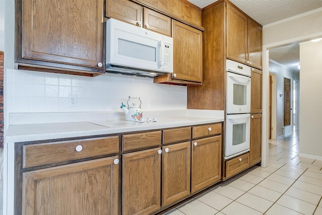 kitchen featuring light tile patterned floors, crown molding, white appliances, a textured ceiling, and decorative backsplash